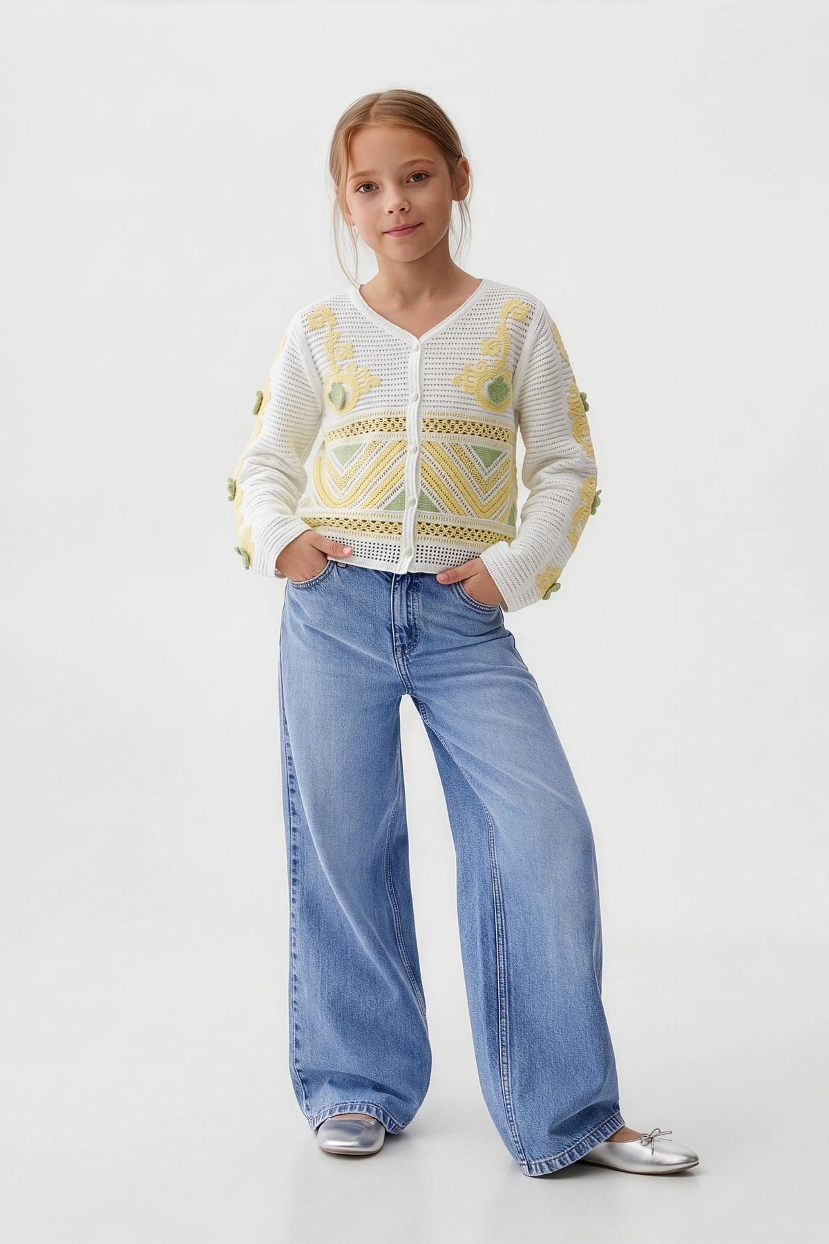 Girl wearing white floral cardigan, wide-leg jeans, and silver flats for casual kids fashion