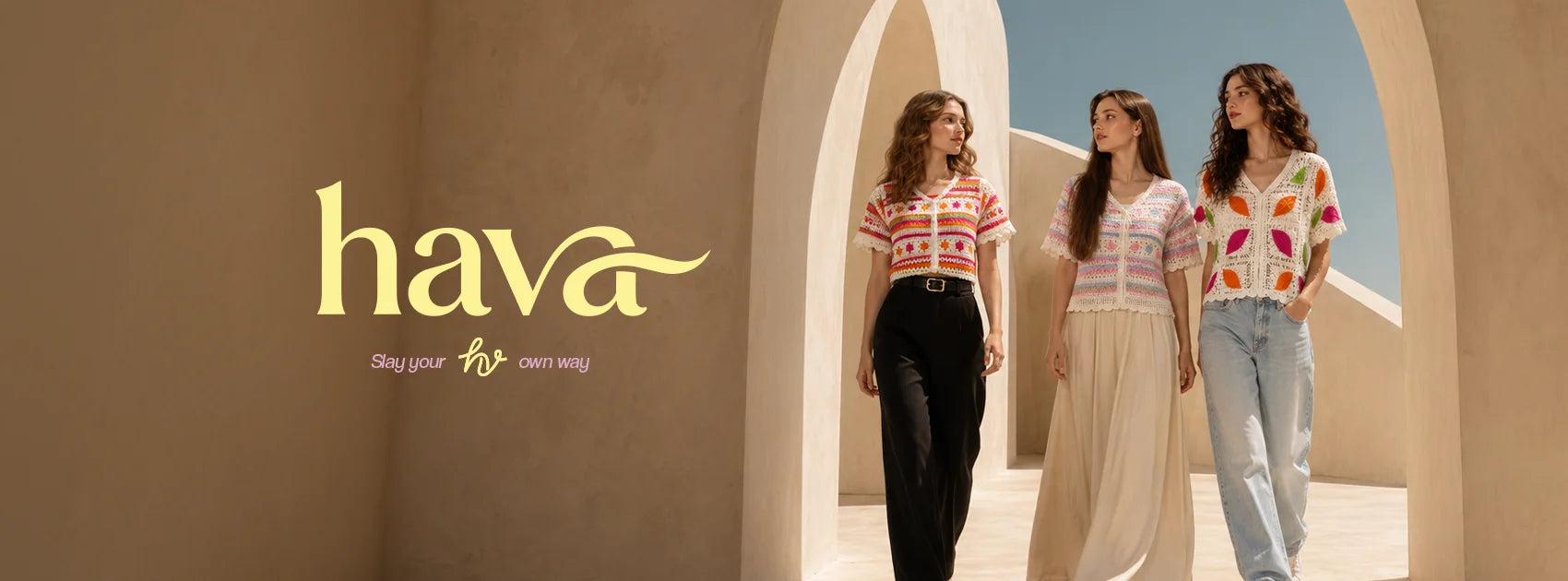 Three women in colorful knit tops and stylish outfits under arched architecture